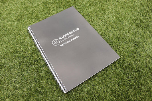 Allenatori Club Match Day Planner spiral-bound notebook with dark grey cover on green grass.